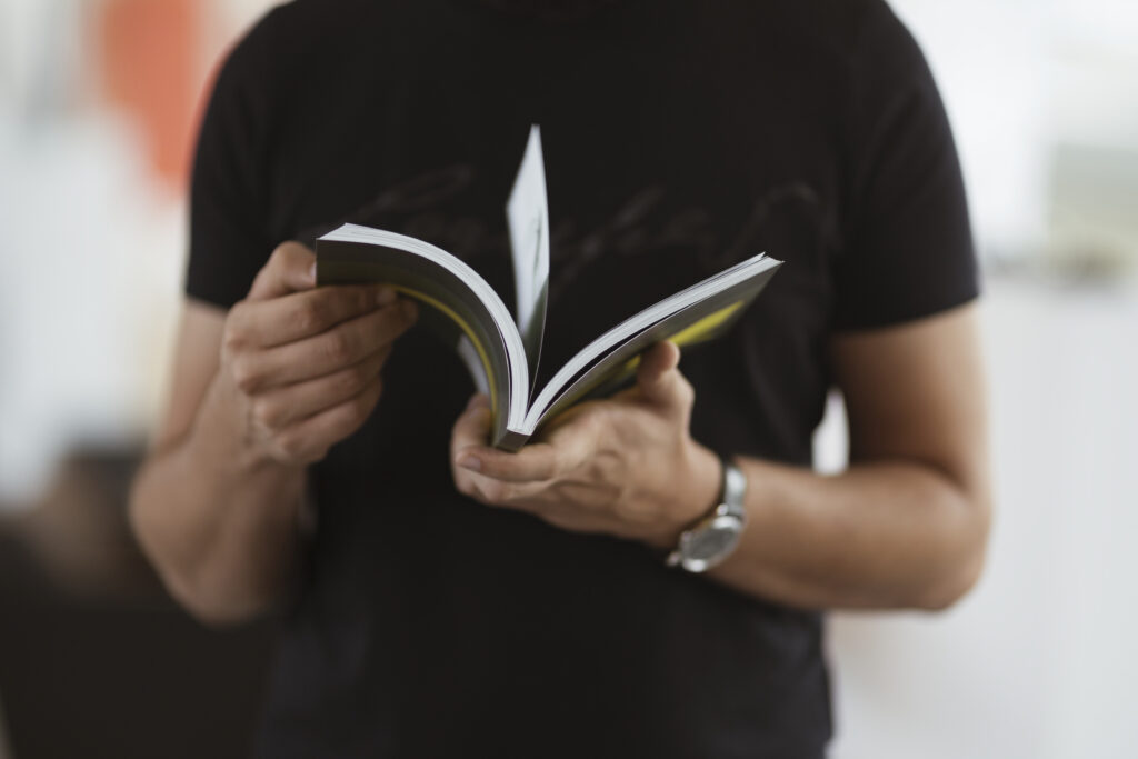 Pessoa folheando um manual de boas práticas, documento essencial para organizar processos e garantir a padronização na empresa