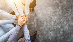 Equipe unindo as mãos representando soluções para problemas de gestão empresarial através do trabalho em equipe e colaboração.